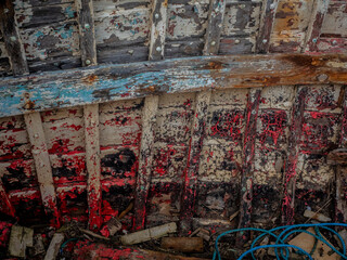 Peeling paint on rotting and weathered wood of old fishing boat