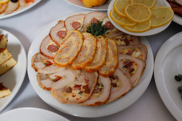 dish with sliced ​​rolls. Slices of meatloaf are laid out on a large white platter, with bits of sausage and vegetables visible in it.
