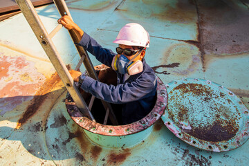 Technician climbing a ladder from a confined space.
