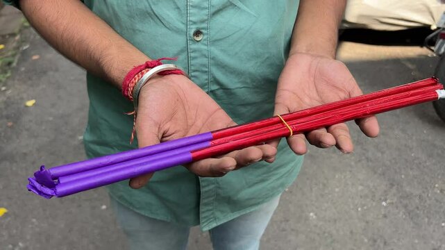 A man stands ready with rang masal firecrackers, poised to light up the night.