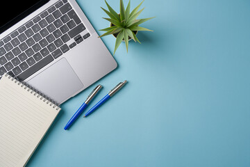 Top view of blue office desk with laptop and supplies. Flat lay business concept