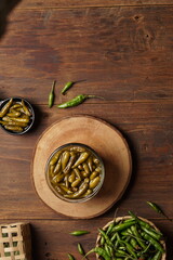 Sweet and sour green chili pickles with brown wood background