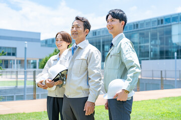 屋外で見上げる作業着を着た男女