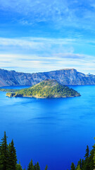 Morning at Crater Lake National Park in Oregon, highlighting the serene, deep blue waters, evergreen forest, and iconic island, creating a tranquil and mystical atmosphere.