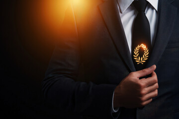businessman in suit adjusts his tie, featuring laurel emblem, symbolizing achievement and success. dark background enhances focus on his confident demeanor