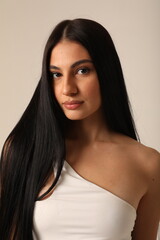 Vertical headshot of beautiful young woman with long dark hair looking at the camera. 