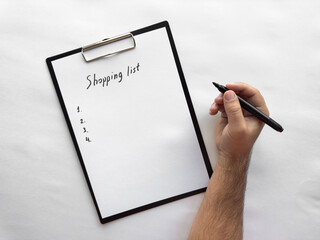 Handwriting a minimalist shopping list on clipboard