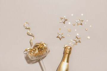 Party fashion background with champagne glass and bottle and golden confetti stars. Christmas, birthday or wedding concept. Flat lay style. © juliasudnitskaya