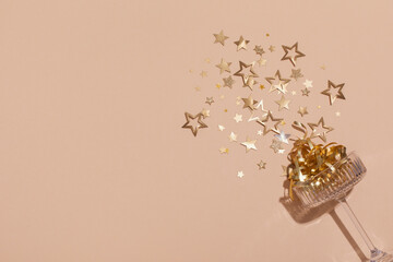 Party fashion background with champagne glass and golden confetti stars. Christmas, birthday or wedding concept. Flat lay style. © juliasudnitskaya