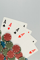 Top view of playing cards, poker chips on grey background. Four aces cards, board game, poker. Copy space, flat lay.