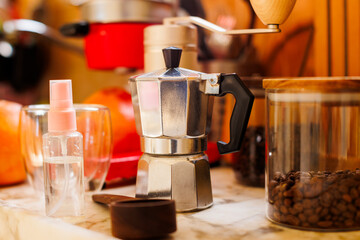 Ingredients for making coffee. Moka pot, bean spray, coffee grinder with coffee beans standing on the kitchen table.