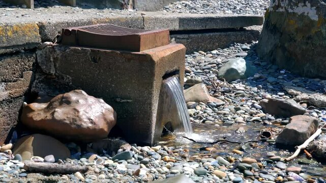 Small Waterfall Flowing Over Gravel from Concrete Block with Gully