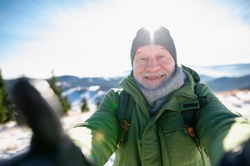 Winter hike for an elderly man in snowy mountains. Active senior enjoying nature.
