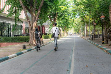 Naklejka premium Commuting to work with bicycle. Young business person cycling and riding electric scooter to office in downtown district. Modern diversity people use eco transportation in city. Sustainable lifestyle.