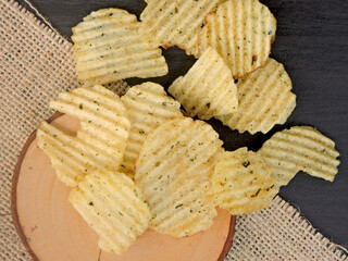 Close-up a bird's eye view of crispy potato chips seasoned with herbs on a white background. Perfect for snack-related themes, food advertising, or culinary concepts