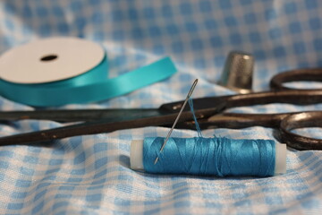 Spool of Blue Thread, Thimble and Needle on Blue and White Fabric