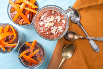 Mocha Mouse or Chocolate mousse with orange candied peels and almond petals in glass glasses on a...