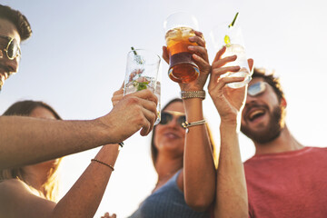 Happy friends toasting with cocktails outdoors against the sky. Concept of summer party,...