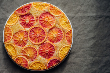 Delisious freshly baked homemade blood orange upside-down cake, top view on grey background. Popular winter holiday dessert. Copy space for text.