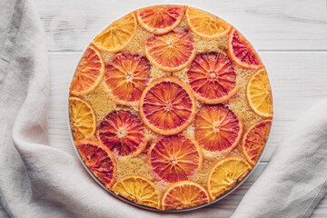 Delisious freshly baked homemade blood orange upside-down cake on white wooden background, top down view. Popular winter holiday dessert.