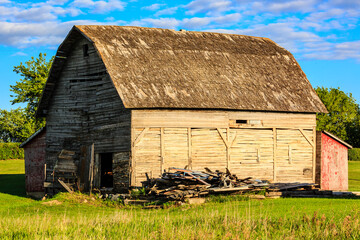 A large, old barn with a red roof sits in a grassy field © Scott Prokop
