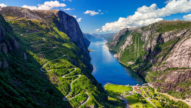 A breathtaking drone aerial view of a Norwegian fjord, showcasing towering cliffs, lush greenery, and the crystal-clear waters of the fjord. Kjerag, Lysebotn, Lysefjorden, Norway