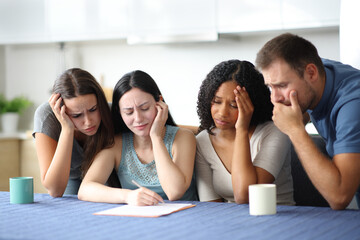 Four sad interracial friends checking contract at home