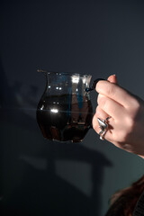 An Elegant Hand Gracefully Holding a Beautiful Glass Jug That is Filled with Dark, Rich Liquid