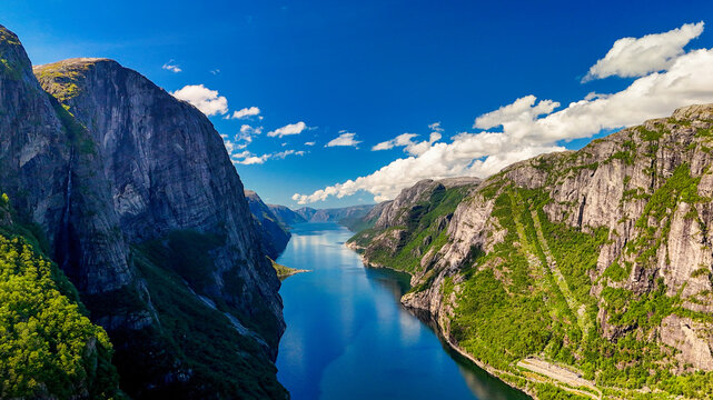 A breathtaking view of a Norwegian fjord, showcasing towering cliffs, lush greenery, and the crystal-clear waters of the fjord. Kjerag, Lysebotn, Lysefjorden, Norway in summer