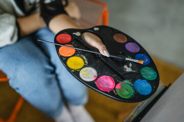 top down of woman artist hands hold color palette and brush