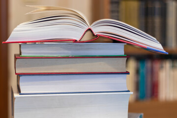 An open book lies on a stack of hardcover books