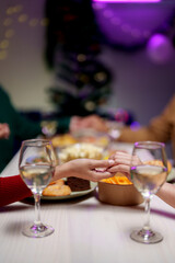 Celebrating Christmas with a group of friends, cheering, Santa hats, gifts, and happy food, wine, and drinks. Hold hands and pray together during the holidays. Holiday celebration ideas.