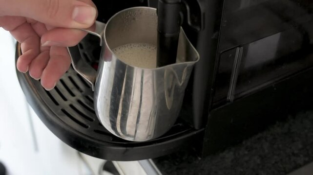 Frothing milk in a home espresso machine, the shot is close up and you can see the milk froth forming.
The cup with milk and foam is half full.