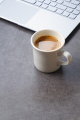 淹れたての美味しいコーヒーを飲みながら、ノートパソコンでデスクワークをしているイメージ
