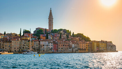 Fototapeta premium As the sun sets over Rovinj, Croatia the shoreline glows with warm colors, highlighting the charming coastal buildings and the iconic bell tower
