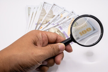 This intriguing image features a magnifying glass examining a stack of prop money, symbolizing financial scrutiny, investigation, and due diligence.