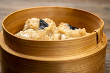 Chinese dim sum dumpling on bamboo wooden basket bowl on wooden table