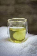 A Beautiful and Vibrant Green Beverage in a Transparent Glass Sitting on a Snowy Surface