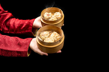 Chinese person holding dim sum dumpling on bamboo wooden basket bowl