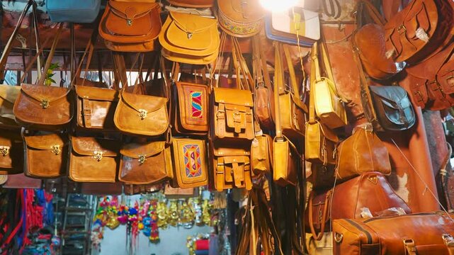 Leather handmade bags on a wall for sale at a local street market in Jaipur, Rajasthan, India. Stylish fashion bag, purse. Shopping in street market. Purses hanging to purchase in shop