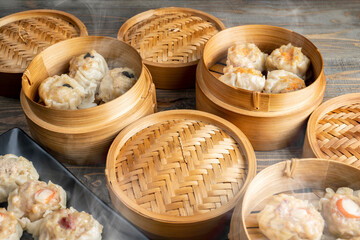 Fototapeta premium Assorted chinese dim sum dumpling on the plate with bamboo wooden basket bowl on wooden table