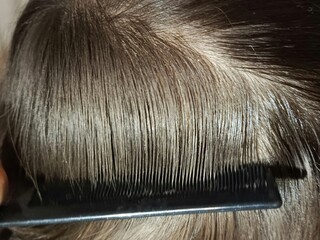 A black comb combs Mocha Mousse colored hair. Hairdressing services. Comb comb.