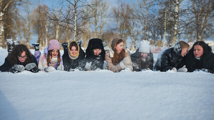 Schoolgirls having fun in the snow and playing together during winter break in the park