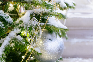 Snow-covered branches of a Christmas tree with New Year decorations. Bright shiny Christmas decorations on a tree.