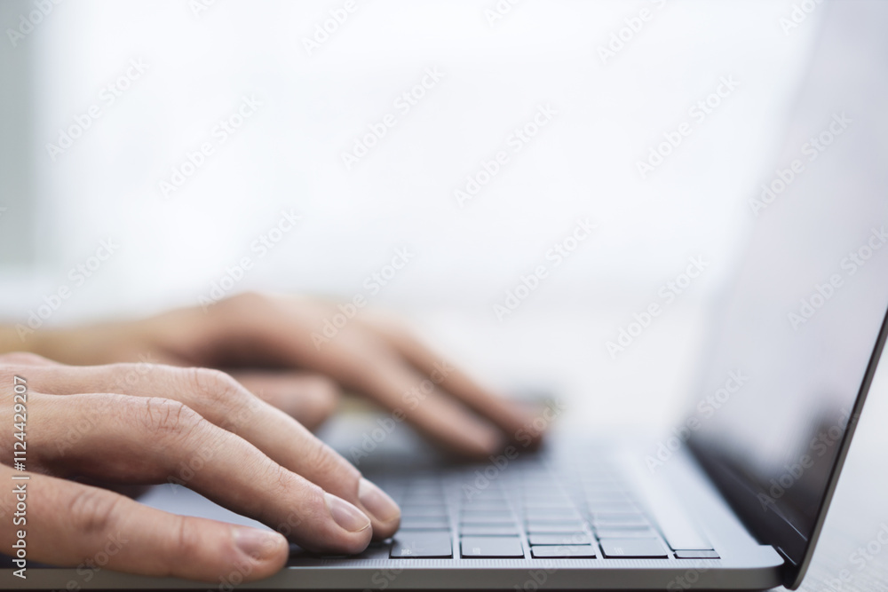 Poster the image presents a man's hands up close as they navigate a modern laptop's keyboard, against a blu