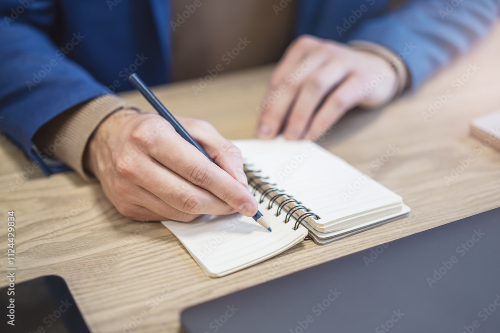 Poster In close view, a man's hand writing down notes in a notepad, against a hazy backdrop