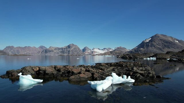Aerial footage of Greenland's landscape. Untouchable and isolated nature. Icebergs and ice floes floating on the calm waters of the Arctic. Glacier visible in the background. Filmed in Greenland. 