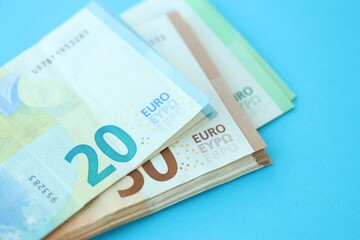 Big amount of one hundred, twenty and fifty euro money bills on blue background
