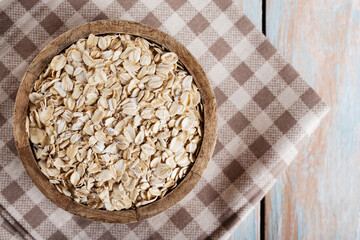 Wooden Bowl with Dry Oatmeal on Checkered Linen Napkin, Top View