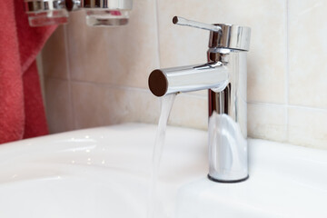 Chrome-plated faucet for the bathroom sink. A mixer with a solid body and Pop-Up Waste